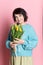 Beautiful old woman with professional smokey make-up and hairstyle holding tulip flowers on the pink background