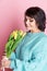 Beautiful old woman with professional smokey make-up and hairstyle holding tulip flowers on the pink background