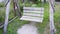 Beautiful old wooden swing from boards and logs in the garden close-up. Empty wood swing seat hanging on chains in