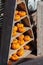 Beautiful orange pumpkins on the decorative wooden shelves of a triangular rack. Harvest Vegetable Shop Decor For Halloween. Small