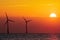 Beautiful orange sunrise behind offshore wind farm turbines