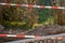 Beautiful ornamented metal fence in foreground with blurred background of red and white temporary tape barrier.