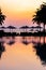 Beautiful outdoor swimming pool with silhouette umbrella chair around in resort at sunrise time