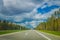 Beautiful outdoor view of highway to the airport of Minsk against dramatic clouds background with trees at each side of