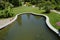 Beautiful oval pond with muddy water and plants in the Park with mowed lawn