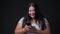 Beautiful overweight Asian woman using mobile phone against black background