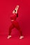 Beautiful overweight woman in comfortable sportswear training, stretching against red studio background. Sport, body