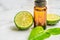 Beautiful packshot of Bergamot essential oil in a small brown glass bottle with fresh bergamot fruit with green leaf on the marble