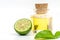 Beautiful packshot of Bergamot essential oil in a small glass bottle with cork, fresh bergamot fruit, and green leaf on white