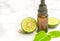 Beautiful packshot of Bergamot essential oil in small glass bottle with fresh bergamot fruit with green leaf on the marble