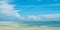 Beautiful panorama of horizon with hazy white tropical clouds above tropical blue empty sea.