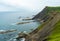 Beautiful panorama of large cliffs with green grass and Atlantic Ocean with tourquoise water