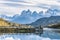 Beautiful panoramic view small people standing at the dock from the lake with Cuernos, horn mountains peak with lenticular cloud