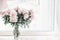 Beautiful pastel pink bouquet of peonies in glass vase on windowsill. Flowers in interior design.