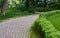 Beautiful paved path in the modern park of tiles and stone with green fences. Without people.