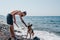 A beautiful pedigreed dog and a man are relaxing in nature on the sea coast. A German shepherd dog plays with its owner on the