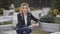 Beautiful pensive blond woman sitting on bench in park outdoors.