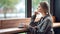 Beautiful pensive blonde unhappy woman looking out of window at rainy autumn day sitting in cafe