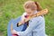 Beautiful pensive dreamy little caucasian girl songwriter sitting on green grass with denim custom guitar