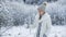 Beautiful pensive girl touching frozen tree in winter forest