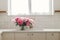 Beautiful peonies in vase in sink on background of brass faucet and window in new scandinavian house. Pink peony flowers in modern