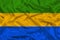 Beautiful photo of the national flag of Gabon on delicate shiny silk with soft draperies, the concept of state power, country life