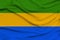 Beautiful photo of the national flag of Gabon on delicate shiny silk with soft draperies, the concept of state power, country life