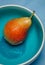 A beautiful photo of a ripen pear in a blue bowl.