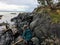 Beautiful photo of a woman hiking a picturesque rocky shoreline surrounded by the vast ocean and first nations petroglyphs