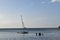 Beautiful picture of a man fishing in a bay close to a sailing boat. Relaxing environment.