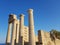 Beautiful pillars of a old ruined building located on the coast of a calm sea against a cloudless blue sky.