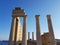 Beautiful pillars of a old ruined building located on the coast of a calm sea against a cloudless blue sky.