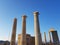 Beautiful pillars of a old ruined building located on the coast of a calm sea against a cloudless blue sky.