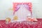 Beautiful pink photo zone for one year old baby girl with paper flowers, wrapped present boxes, wooden castle and princess carriag