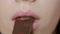 Beautiful pink plump lips close-up bite of chocolate, young girl