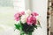 Beautiful pink and white peonies bouquet at rustic old wooden window. Floral decor and arrangement. Gathering flowers. Rural still