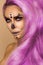 Beautiful pink woman in Halloween makeup and in pink hair on a beige background in the studio. Makeup artist skeleton, monster,