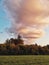 Beautiful pink yellow red purple evening sky clouds in forest park. Landscape scene view with grass field meadow, trees. Twilight