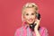 Beautiful pinup woman answers a phone call on red background