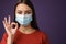 Beautiful pleased girl in protective mask showing ok sign