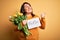 Beautiful plus size woman celebrating mothers day holding best mom message and tulips pointing and showing with thumb up to the