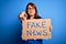 Beautiful plus size woman holding fake news banner for false journalism over  background pointing with finger to the