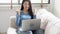 Beautiful portrait asian young woman working online laptop with smile and happy sitting on couch at living room