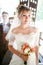 Beautiful portrait of bride with groom behind glass, wedding bouquet in hands indoors.