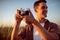 Beautiful portrait of handsome smile young man with vintage camera,on a meadow background. Travel mood. Photography.