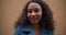 Beautiful portrait of happy calm mixed race 20-25 woman with curly hair looking right, posing at camera slow motion.