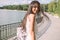 Beautiful portrait of happy young brunette woman with beautiful smile, with a windy long hair, on park background with a lake.