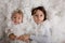 Beautiful portrait of three sibling boys, lying on the floor in a pile of cotton, holding hands, looking at camera