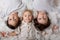 Beautiful portrait of three sibling boys, lying on the floor in a pile of cotton, holding hands, looking at camera