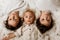 Beautiful portrait of three sibling boys, lying on the floor in a pile of cotton, holding hands, looking at camera